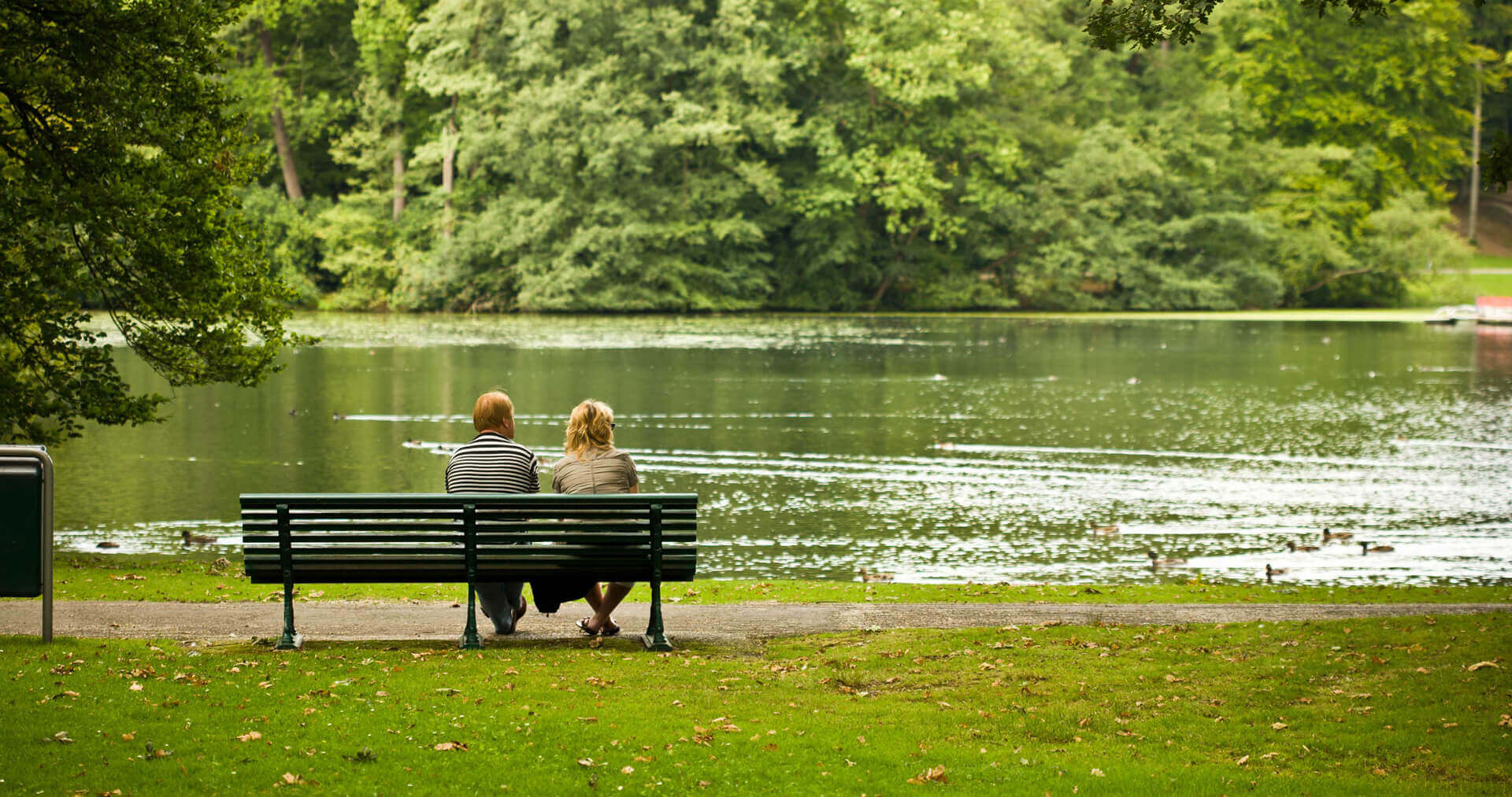 Couple sitting on bench next to lake